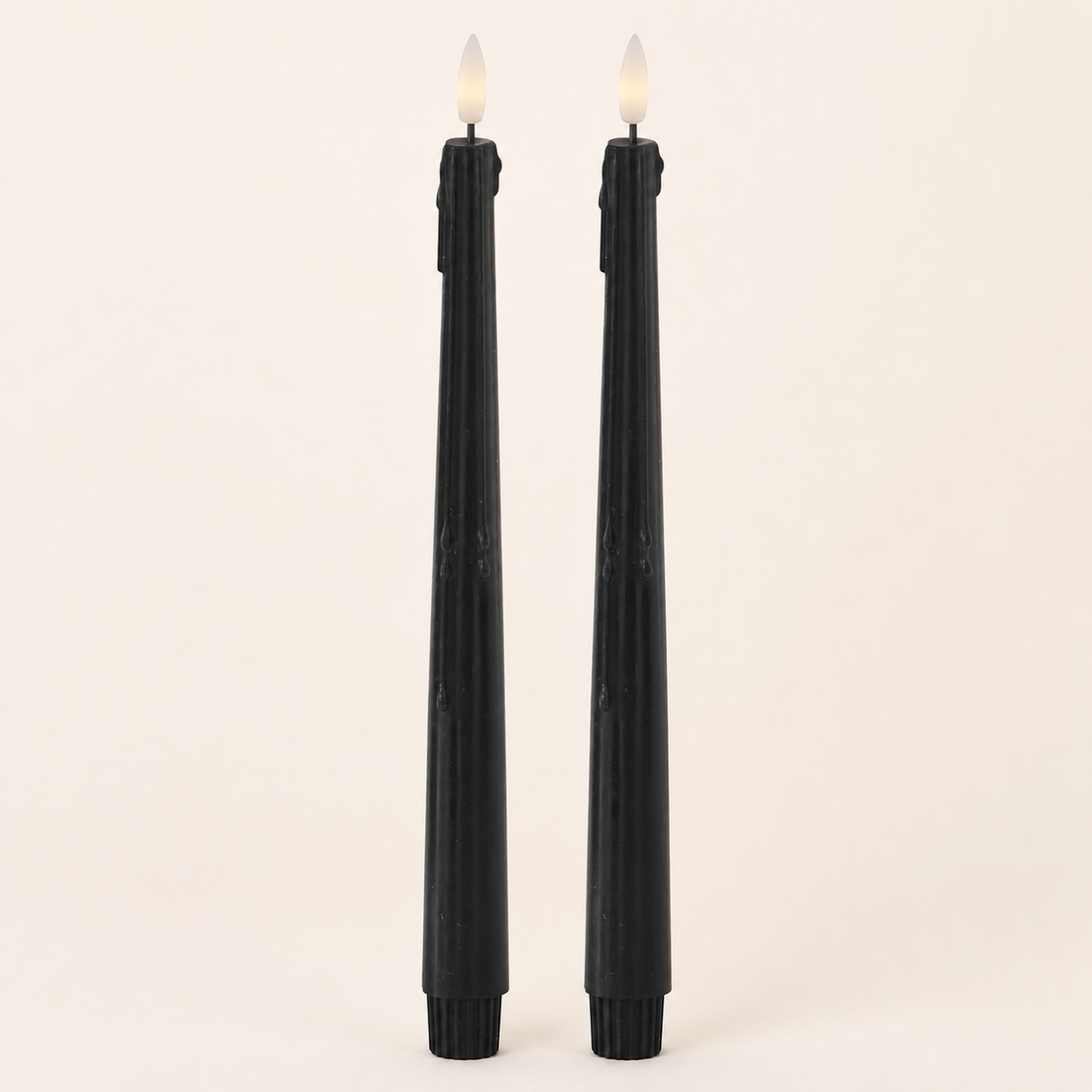 Set of two black LED drip taper candles on a warm neutral catalog background