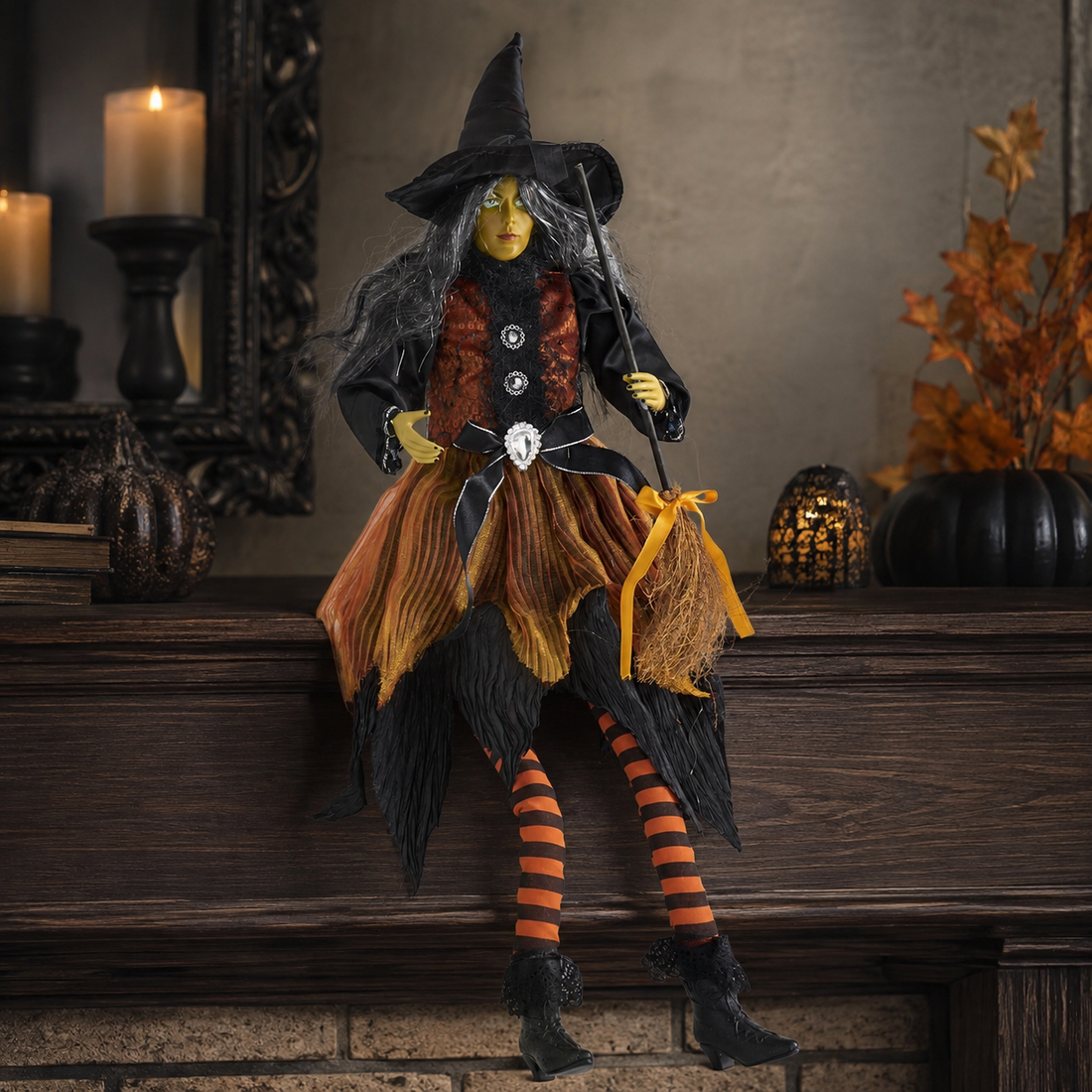 Sitting Sybil witch Halloween shelf sitter with orange dress and broom on a mantel